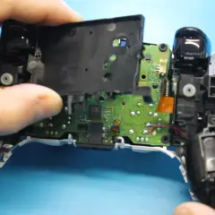 Rozkręcony pad PS5, widoczna płyta główna i elementy mechaniczne. Trwa naprawa pada PS5.
