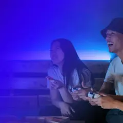Trzech przyjaciół gra w gry wideo, śmiejąc się i jedząc pizzę. To świetna zabawa, jak na Steam!