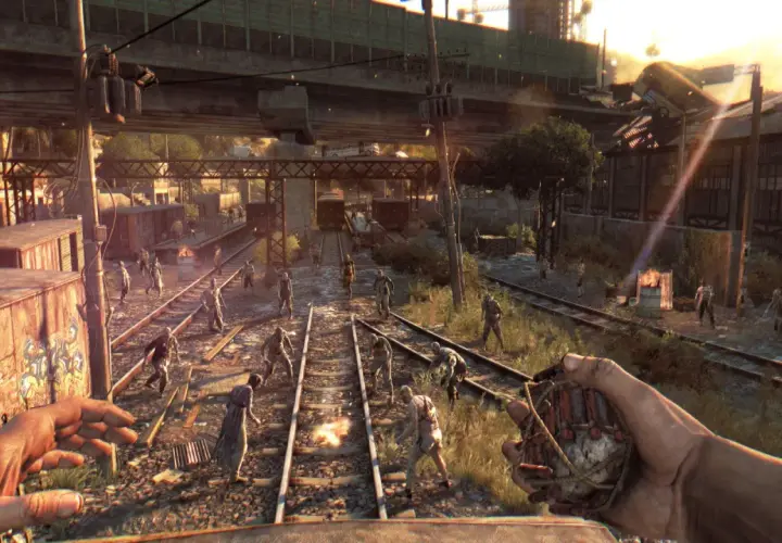 Gracz z granatem w ręku, otoczony przez hordę zombie na torach kolejowych. To scena z gry Dying Light, gdzie wymagania sprzętowe są kluczowe dla płynności rozgrywki.