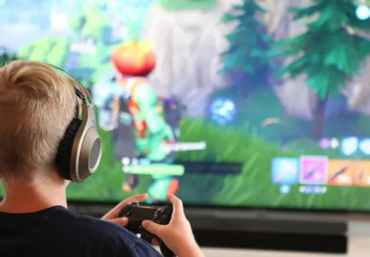 Chłopiec w słuchawkach gra w Fortnite na konsoli. Chcesz wiedzieć, jak zainstalować Fortnite?