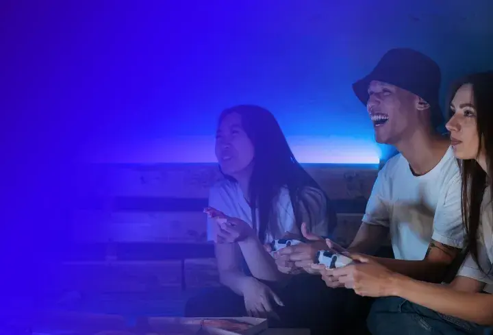 Trzech przyjaciół gra w gry wideo, śmiejąc się i jedząc pizzę. To świetna zabawa, jak na Steam!
