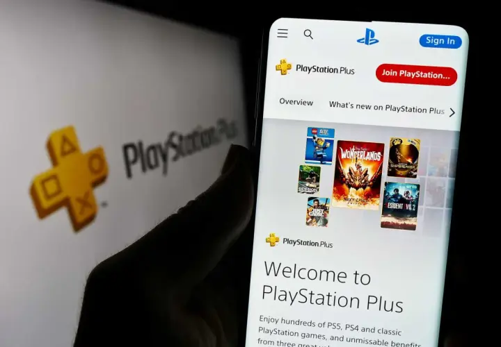 Gry co miesiąc PS Plus na ekranie telefonu, obok logo PlayStation Plus.