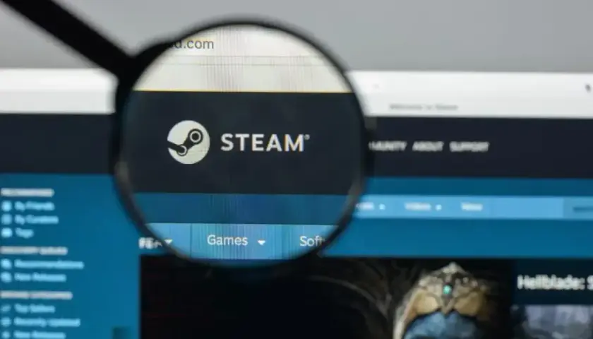 Lupa powiększa logo Steam. Użytkownik szuka informacji o adresie rozliczeniowym Steam, przeglądając stronę główną platformy z grami.