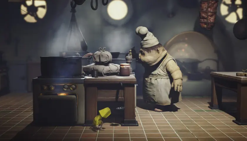 Mały kucharz z Little Nightmares gotuje w kuchni. Pod stołem ukrywa się dziewczynka w żółtym płaszczu.