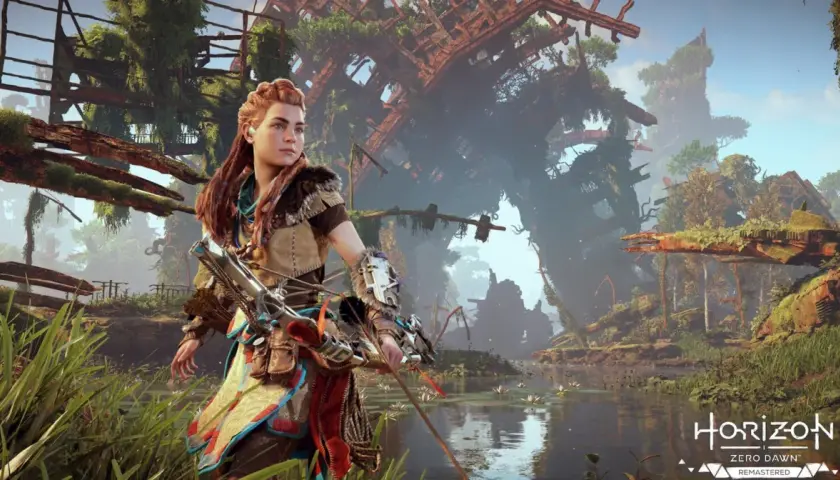 Aloy w Horizon Zero Dawn Remastered, z łukiem w ręku, stoi nad wodą wśród bujnej roślinności i zrujnowanych budowli.