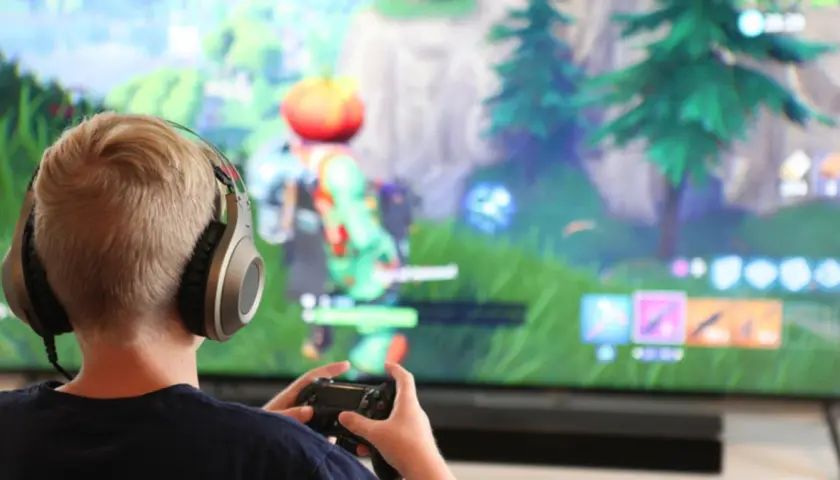 Chłopiec w słuchawkach gra w Fortnite na konsoli. Chcesz wiedzieć, jak zainstalować Fortnite?