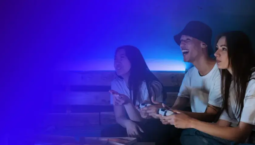 Trzech przyjaciół gra w gry wideo, śmiejąc się i jedząc pizzę. To świetna zabawa, jak na Steam!