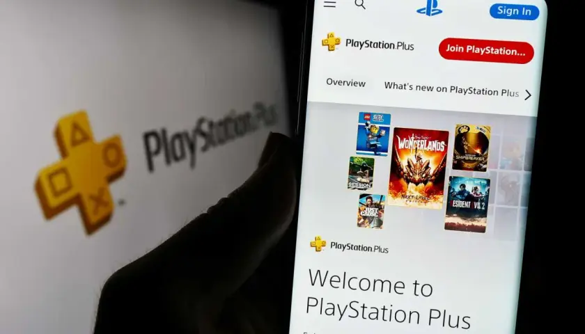 Gry co miesiąc PS Plus na ekranie telefonu, obok logo PlayStation Plus.