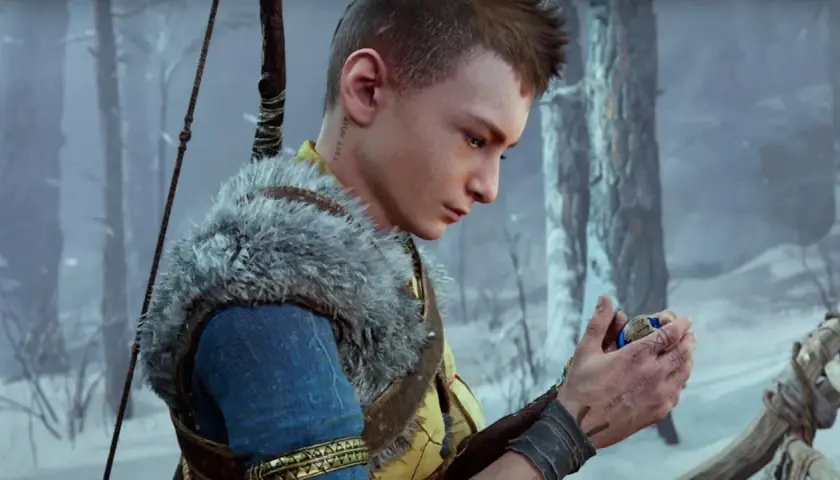 Atreus zamyślony, trzyma w dłoni amulet. W tle zimowy las.