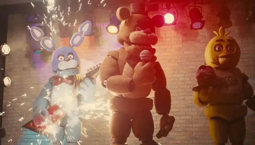 Freddy, Bonnie i Chica z filmu FNAF na scenie. Bonnie gra na gitarze, Freddy śpiewa, a Chica trzyma babeczkę.