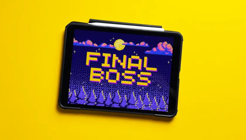 Tablet z grą retro, na ekranie napis "FINAL BOSS" w pikselowym stylu, nocny krajobraz z księżycem i chmurami.