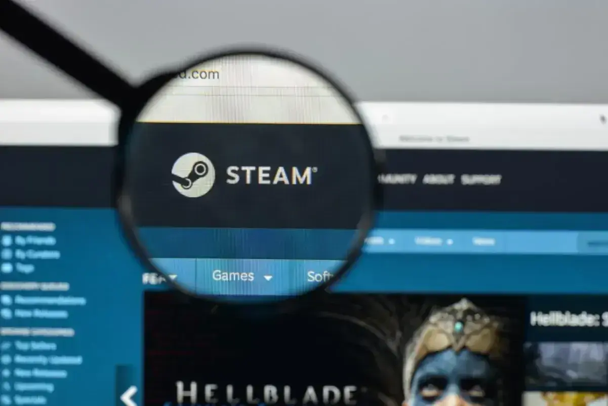 Lupa powiększa logo Steam. Użytkownik szuka informacji o adresie rozliczeniowym Steam, przeglądając stronę główną platformy z grami.