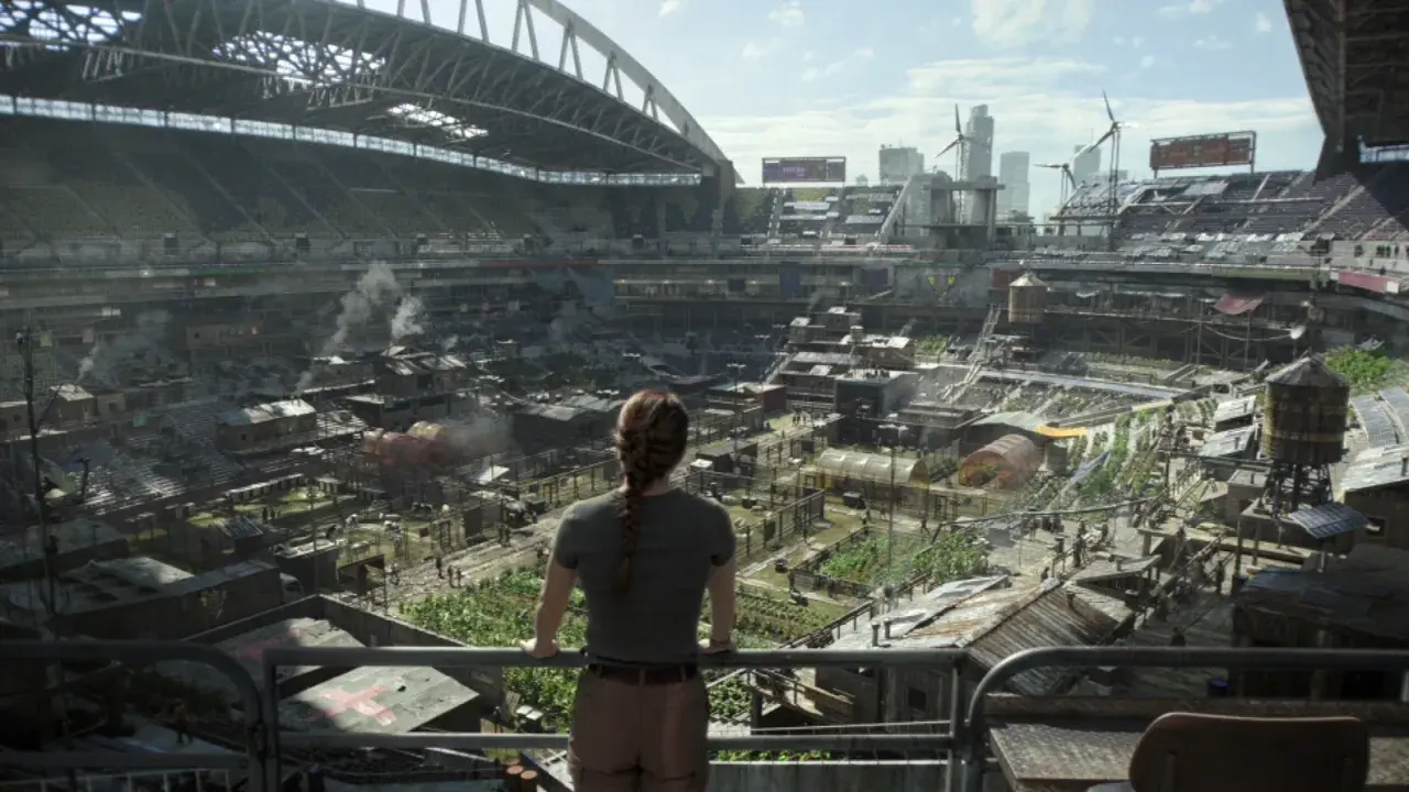 Widok na postapokaliptyczne miasto wewnątrz stadionu, gdzie ludzie żyją w prowizorycznych domach. Może to być scena z The Last of Us sezon 3.