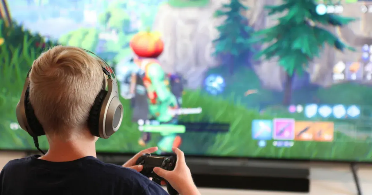Chłopiec w słuchawkach gra w Fortnite na konsoli. Chcesz wiedzieć, jak zainstalować Fortnite?