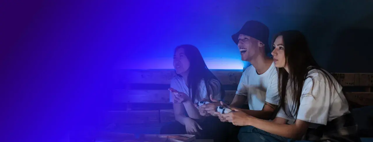 Trzech przyjaciół gra w gry wideo, śmiejąc się i jedząc pizzę. To świetna zabawa, jak na Steam!