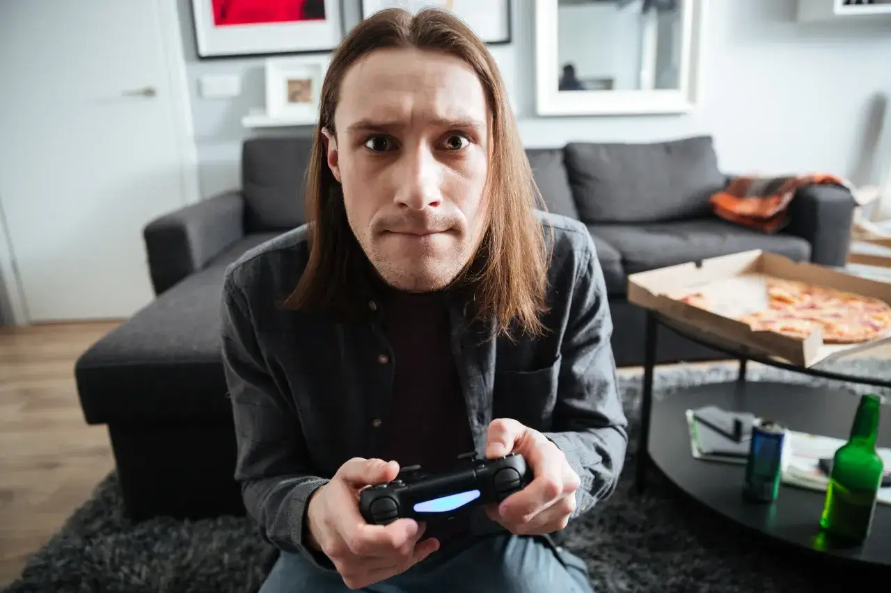 Zaangażowany gamer z padem w dłoniach skupiony na ekranie