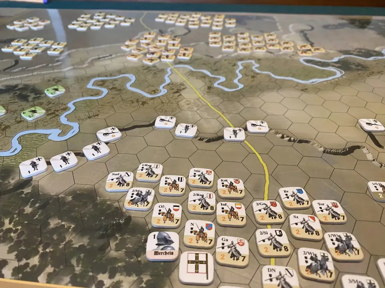 Plansza strategiczna gra turowa z pionkami wojsk. Bitwa na heksagonalnej mapie z rzekami i drogami.