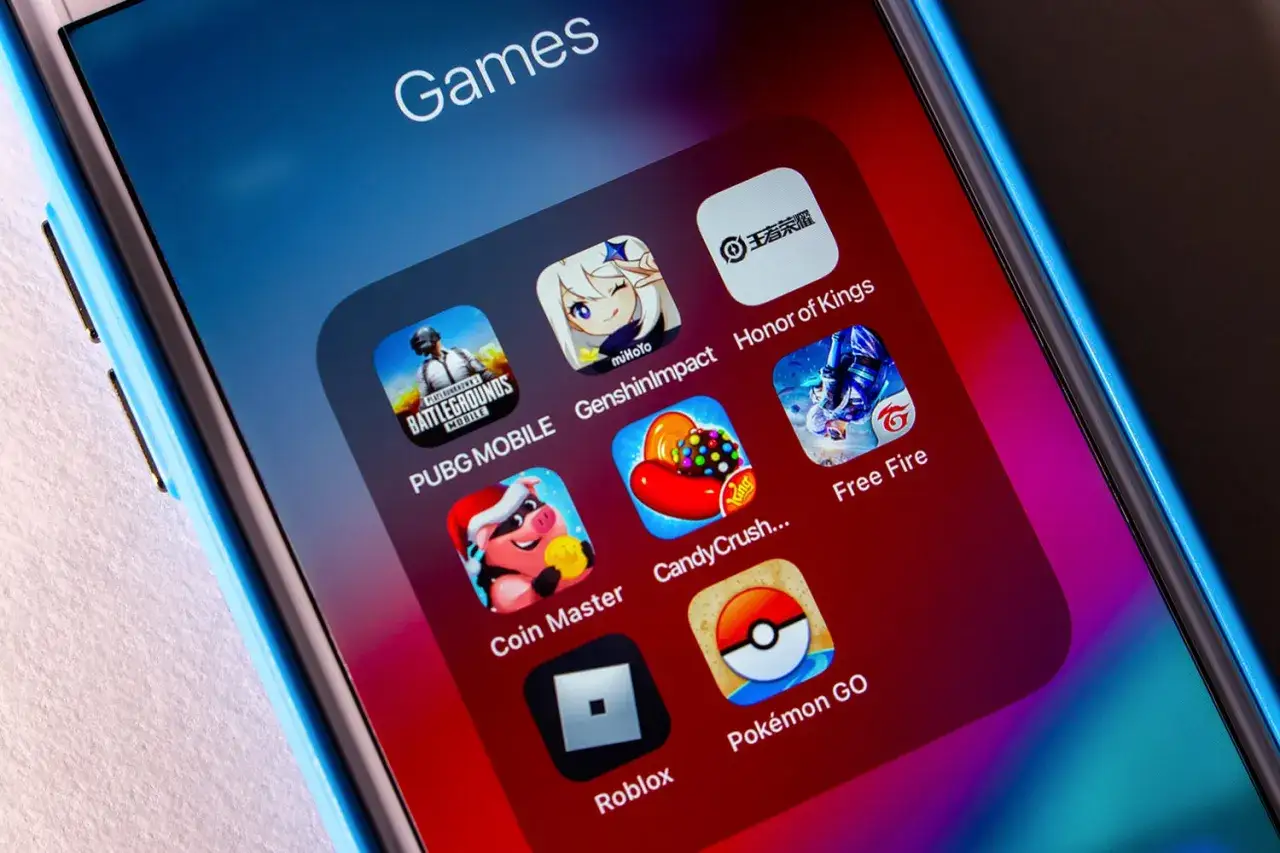 Ekran telefonu z ikonami najpopularniejsze gry na telefon: PUBG MOBILE, Genshin Impact, Honor of Kings, Free Fire, Coin Master, Candy Crush, Roblox, Pokémon GO.
