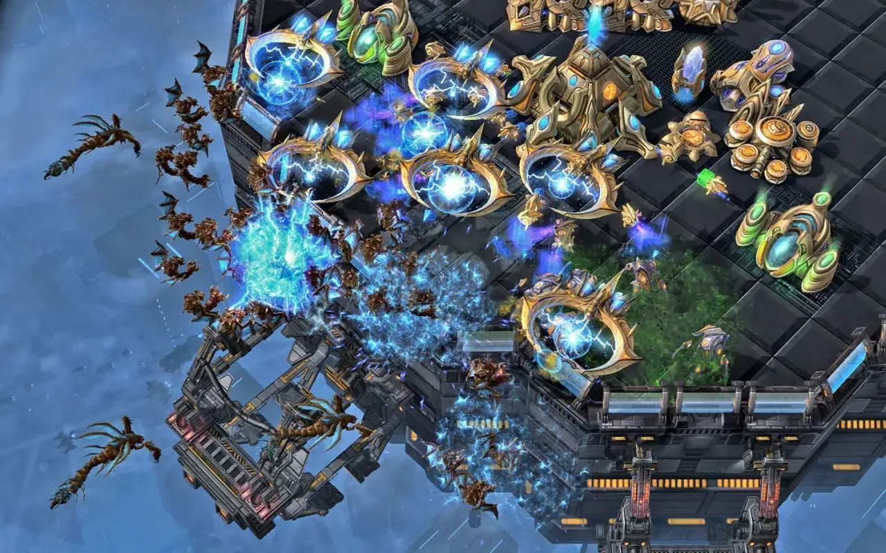 StarCraft II: Zerg atakują bazę Protossów. Widać roje Zergów, w tym Hydraliski i Mutaliski, w starciu z potężnymi jednostkami Protossów, takimi jak Kolosy i Gwiezdni Niszczyciele. To klasyczne rts!