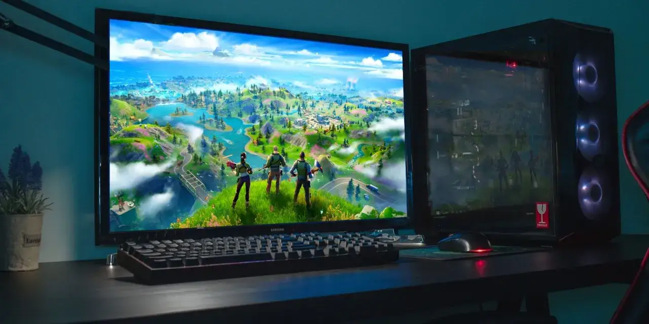 Komputer gotowy do gry! Na monitorze widać mapę z Fortnite, a obok klawiatura i myszka. Chcesz wiedzieć, jak zainstalować Fortnite?